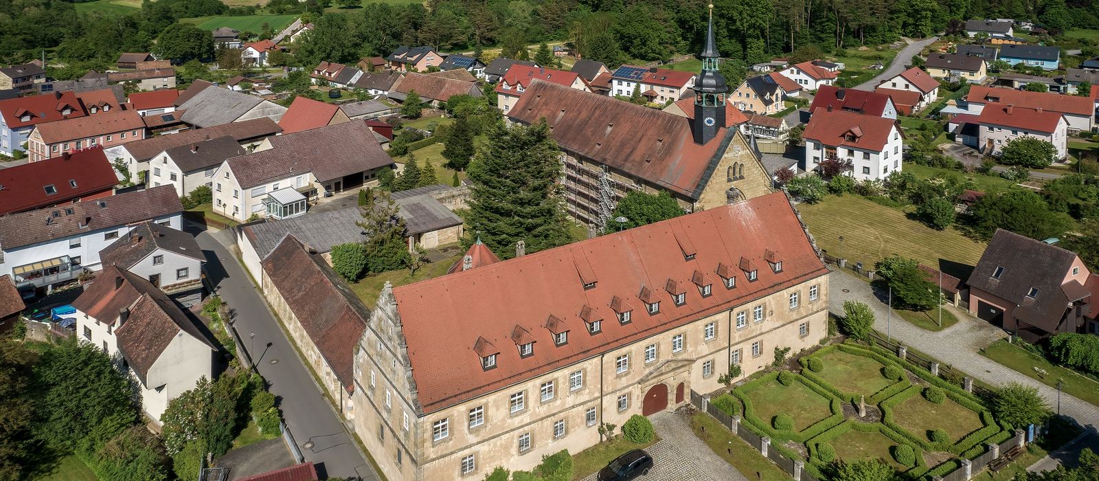 Luftaufnahme einer Ortschaft mit Wohnhäusern und historischem Gebäude