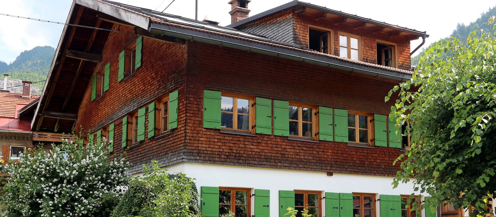 Wohnhaus mit Holzfassade und grünen Fensterläden