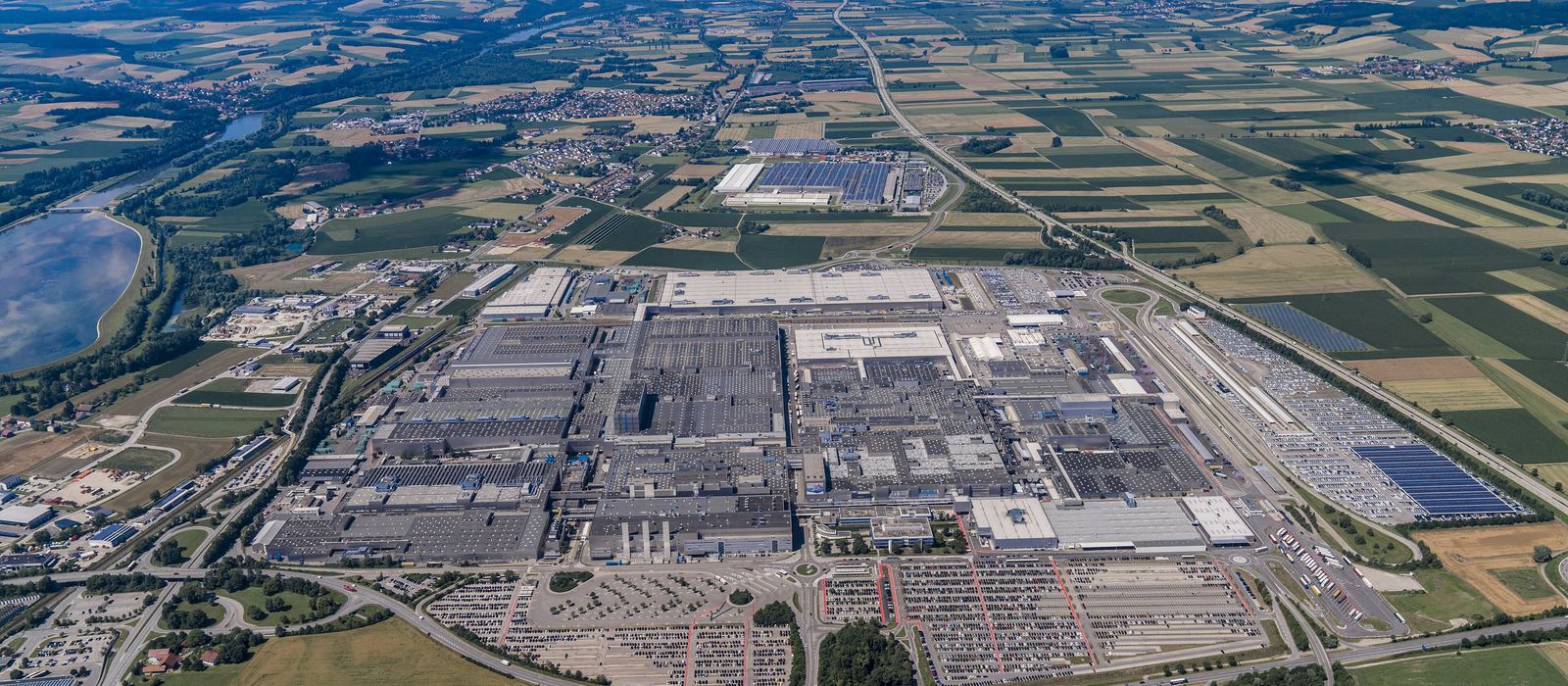 Luftaufnahme eines großen Industriestandorts mit Hallen und Parkflächen